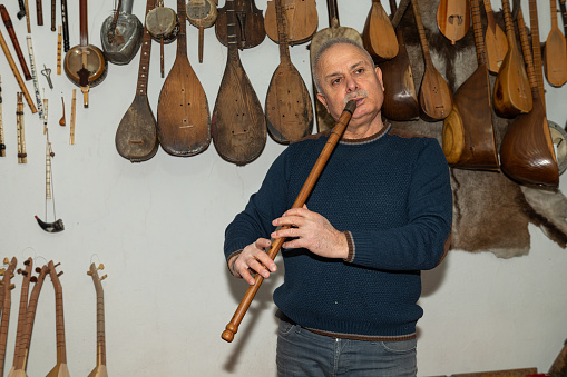 Man playing woodwind musical instrument wooden pipe. Turkish name kaval