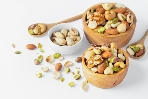Mixed nuts in wooden bowl isolated on white background