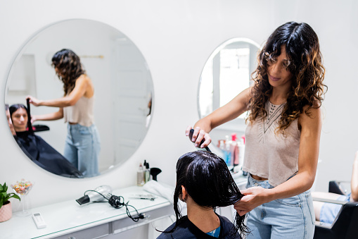 Woman hairdresser combing the customer's hair on a hair salon