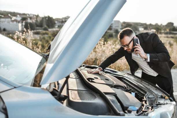 istock Businessman Looking For Damaged Tubes In Car While Talking To Mechanic Over Smartphone While On The Road 2032513728