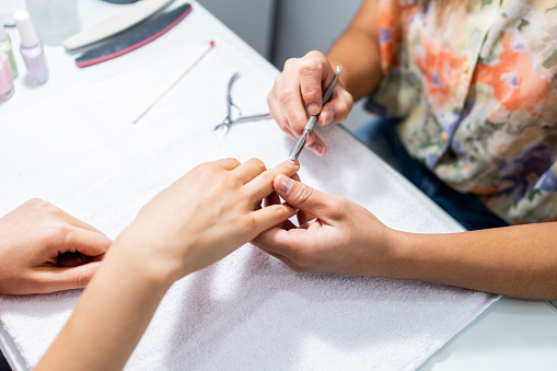 Close-up of a manicurist doing customer's nails in a beauty spa