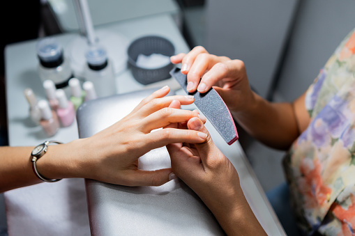 Close-up of a manicurist sanding customer's nails in a beauty spa
