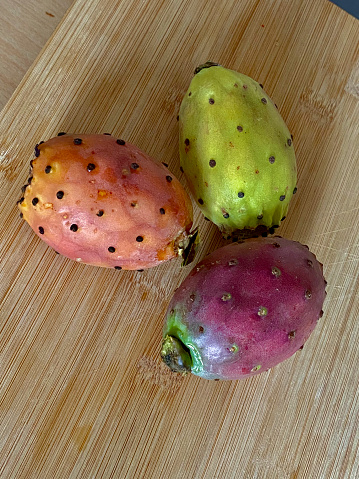 Three prickly pear fruits on a wooden chopping board. A selective approach.