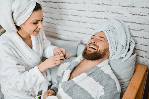Laughing Male Getting Cucumber Slices On Eyes While Doing Girlfriend's Skincare Routine