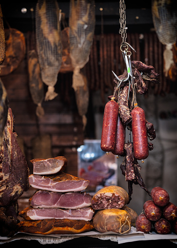 Hanging on hook pork cured meat market store butcher cured smoked pancetta and sausages copy space