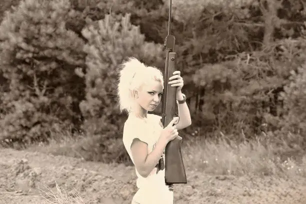 A young beautiful blonde girl shoots from a rifle. Air rifle shooting as a hobby.