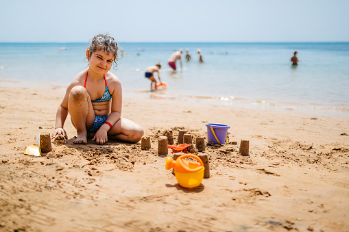 kids play with sand on summer beach, family vacation