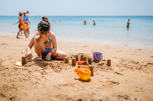 Beautiful little girl playing on the beach, making a sand castle, in Hurghada in Egypt.