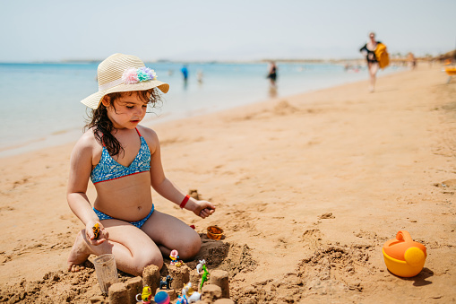 Beautiful little girl playing on the beach, making a sand castle, in Hurghada in Egypt.