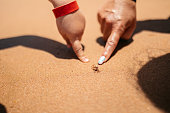 Young Mother And Daughter Pointing At A Small Crab On The Beach In Hurghada In Egypt