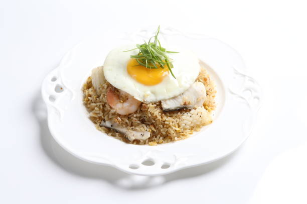 wok garlic fried egg rice with mixed seafood fish, prawn, squid, octopus, fried egg and vegetables in plate on vintage table cloth white background asian chef cuisine halal food menu for cafe