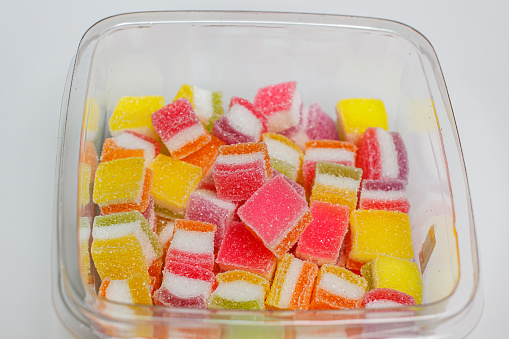 A pile of fruity gummy jelly sweets on white plate background.