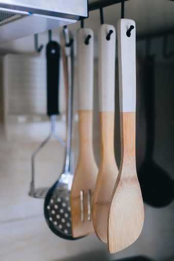 Wooden spoons hanging on hooks in a kitchen