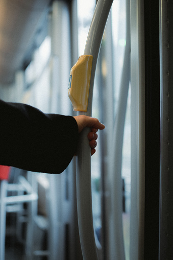 A person gripping a yellow handle in a train