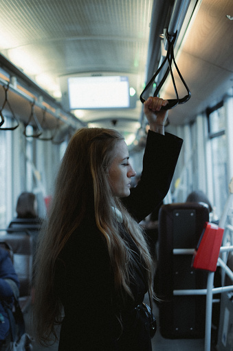 A woman with flowing long hair holds onto bus handrails