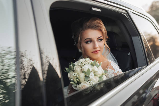 istock A blonde bride, smiling sincerely, sits in a black car 2032626655