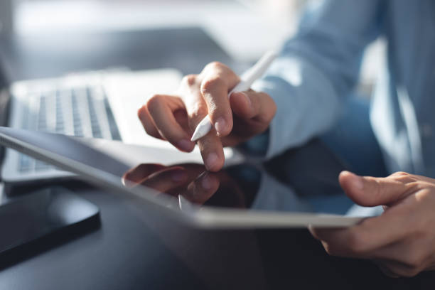 istock Close up, business man using stylus pen, digital tablet with laptop computer on office desk. Businessman reading, proofing digital business document during working at modern office 2032627769