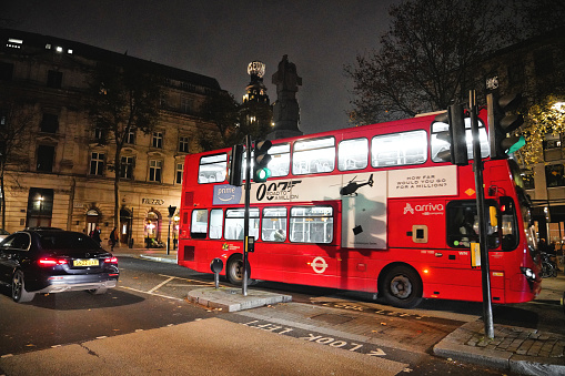 Central London, England United Kingdom - 11 November 2023: \n\nA Night street view of the road junction of Charing Cross Road and St Martin's Place in the West End of Central London, Inner London, England, United Kingdom, with an iconic red double-decker bus, people, cars, and activity on the road and street.