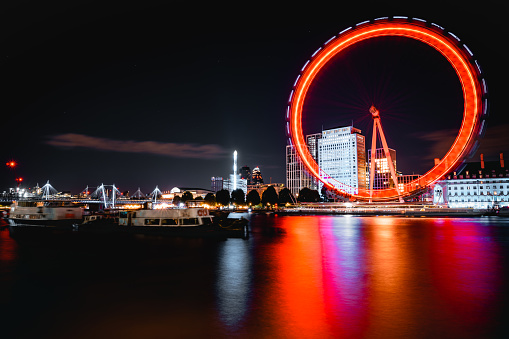 A large illuminated ferris wheel against a backdrop of colorful lights, London, UK