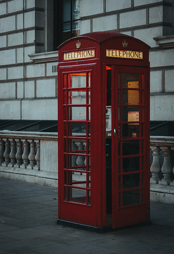 A phone booth on a sidewalk by a building, London, UK