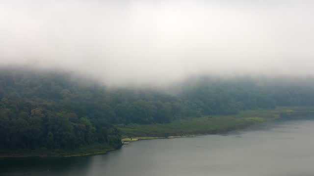 Timelapse of the fog on the Tamblingan Lake encompassed by dense forest, Bali, Indonesia