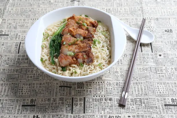 cook Japanese instant noodle mee soup with chicken chop cutlet and vegetables on bowl chopstick on white vintage newspaper background asian chef halal food restaurant banquet menu