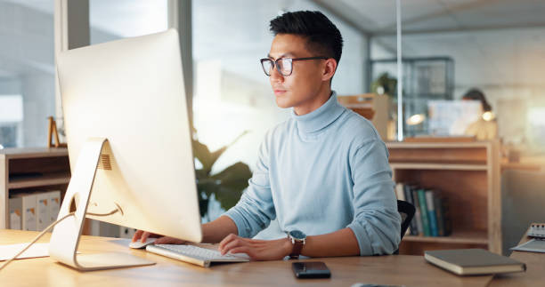 istock Asian man at computer, glasses and ideas, thinking and reading email, web review or article at digital agency. Research, reflection and businessman at tech startup networking on business website. 2032671647