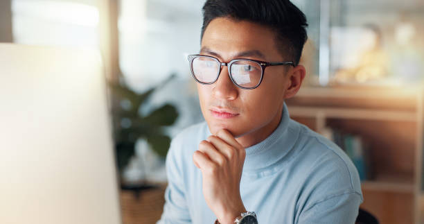 istock Man at computer, glasses and reflection, thinking and reading email, review or article at digital agency. Internet, research and Asian businessman at tech startup with report, networking or feedback. 2032671651