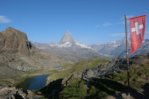 Swiss flag and Matterhorn under a clear blue sky