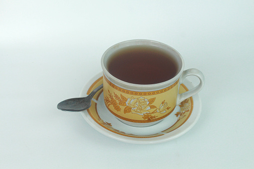 A tea in white ceramic cup with a luxurious floral pattern.