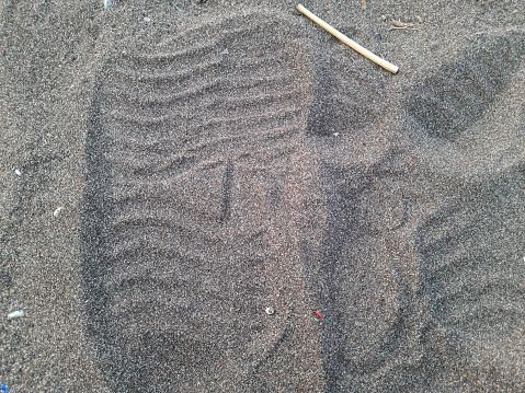 Human footprint on sand with sunset beach background