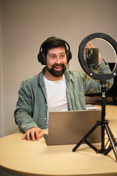 istock Smiling man podcasting using laptop at home 2032717298