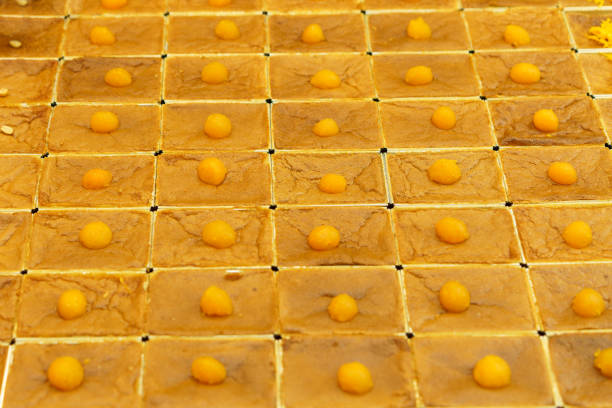 Uniformly arranged Thai dessert, Mo Kaeng, with small golden spheres made from egg yolks and sugar, set on square-cut, representing the traditional art of Thai dessert making