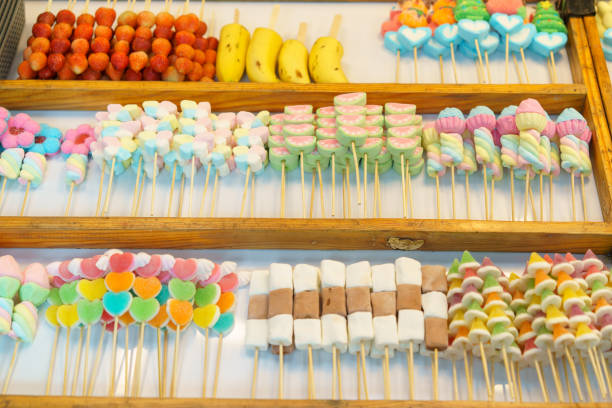 A delightful selection of colorful candy skewers, including marshmallows and jelly candies, displayed at a market stall for sale