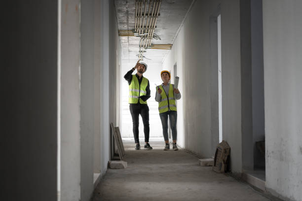 istock Hispanic latin engineer man and woman working with tablet computer and paper work in building at construction site 2032780384