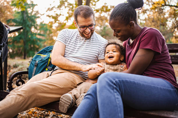 istock Mixed race couple is sitting on a park bench with their son 2032787249