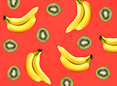 Banana and kiwi on the red background. Flat lay. Pattern. Top view.