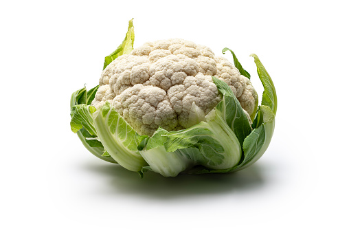 Blanched cauliflower in a colander on a white wooden table