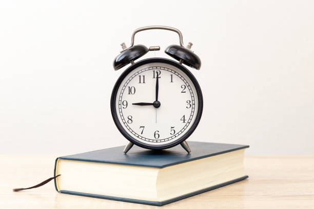 istock A thick book and a clock on the desk. 2032858815