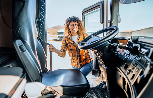 Cheerful female driver entering in truck cabin