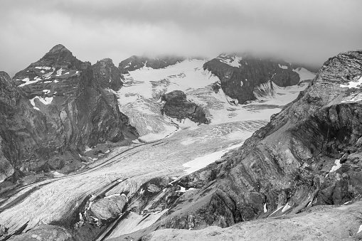 The Ortler Alps near Stelvo Pass at sunset in summer, clouds around the peak, black and white