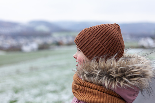 Young girl looking at a snow covered landscape in winter, UK.