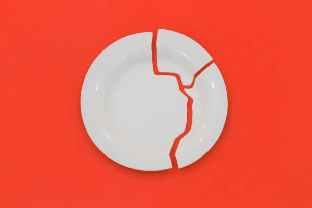 istock Top view on broken circle white plate on red background. The plate broke into three pieces. 2032895158