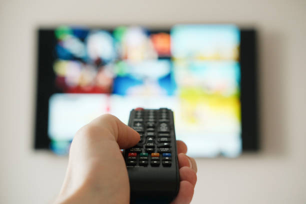 istock Tv remote controller in hand of customer looking for content in Smart Tv app. Watching streaming services on television. 2032895161