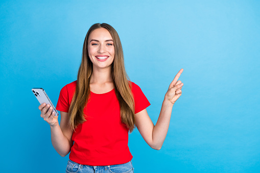 Photo of satisfied adorable girl popular blogger recommend buy novelty empty space isolated on blue color background.