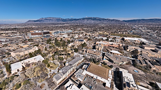 UNM Campus with Sandia mountains from a drone, showing the duck pond, Popejoy hall, and the Zimmerman library