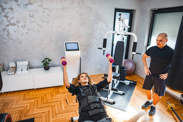 istock Young woman doing upper body exercise with her personal instructor in EMS fitness studio 2032915611