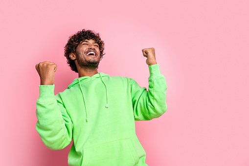 Photo of crazy guy in green trendy pullover enjoy adidas brand outlet clothing for sale raised fists up isolated on pink color background