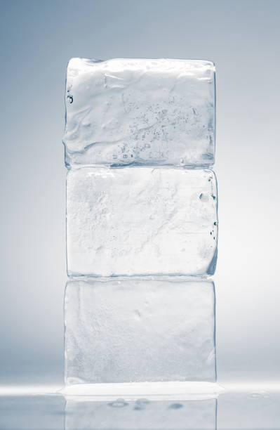 Kristallklare Eisblöcke in rechteckiger Form, gestapelt auf einer Spiegelfläche auf weißem Hintergrund. – Foto