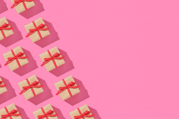 istock Banner with pattern of brown gift boxes on with red bows on pink background. Copyspace. 2032966305